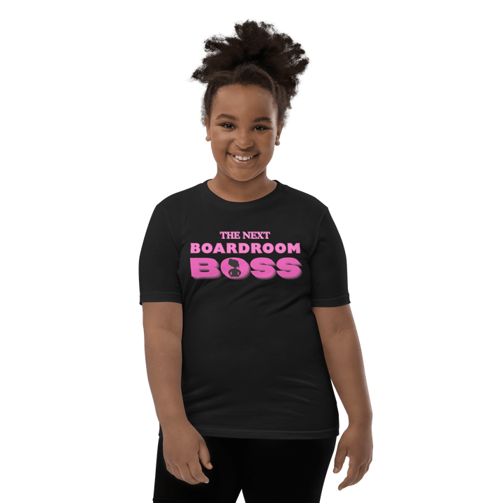 Young Black girl smiling in Pink and black The Next Boardroom Boss T-shirt from TL Johnson’s Mini Monarchs line; empowerment apparel for future leaders.