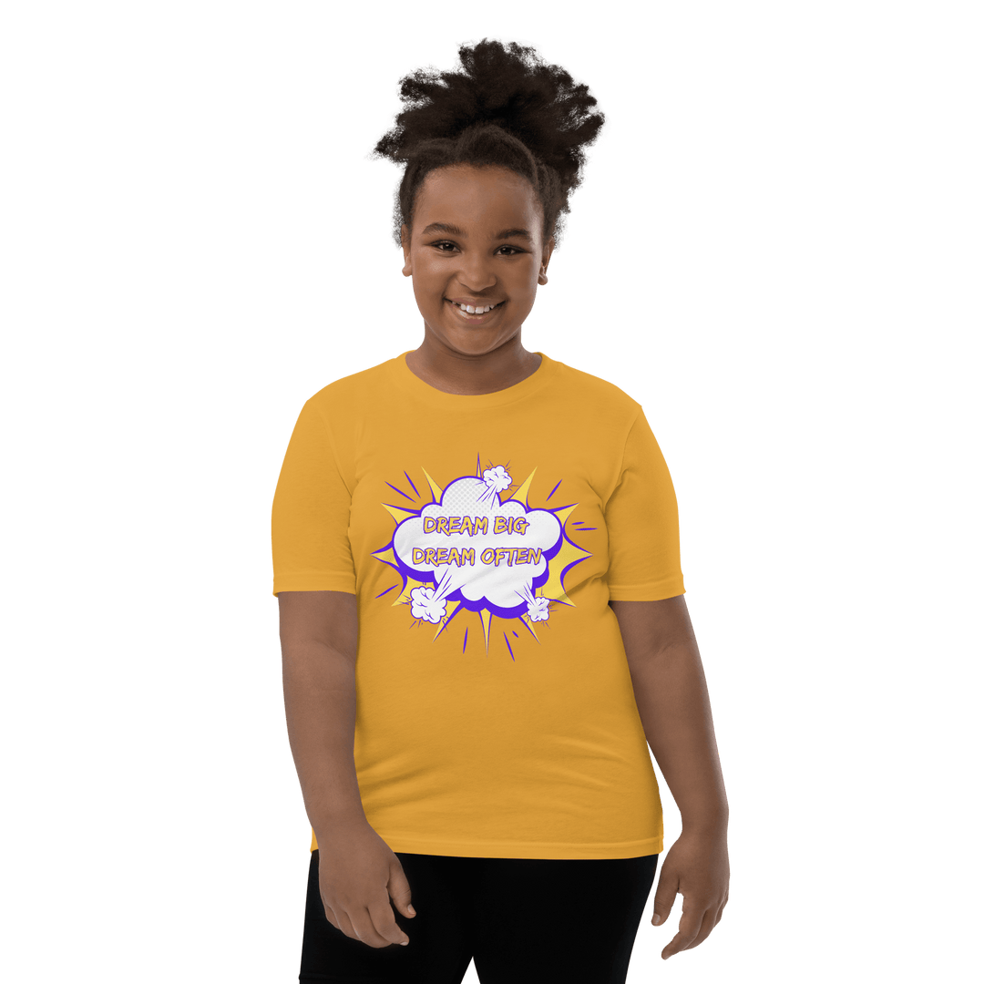 Young Black girl wearing Gold Dream Big T-shirt inspired by TL Johnson’s Dream Big Coloring Book: Careers in Black Excellence; empowerment apparel celebrating career goals.