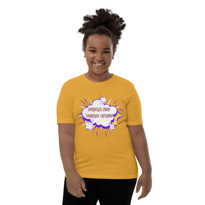 Young Black girl wearing Gold Dream Big T-shirt inspired by TL Johnson’s Dream Big Coloring Book: Careers in Black Excellence; empowerment apparel celebrating career goals.