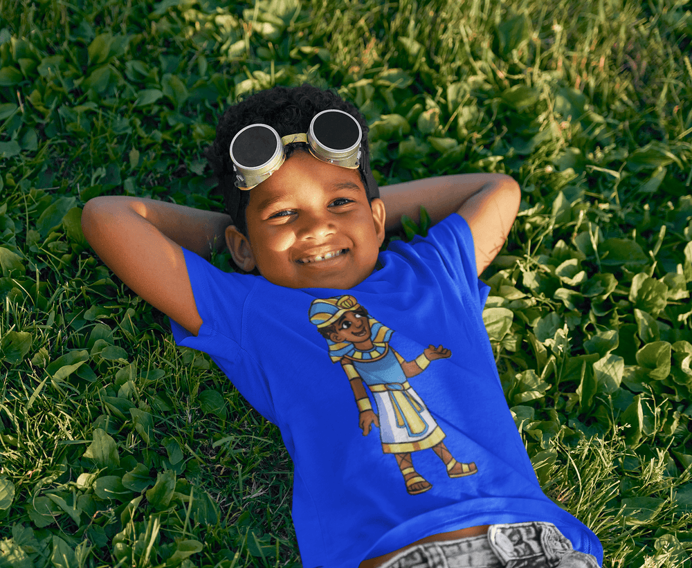 Black boy wearing Tut “Lead With Wisdom” T-shirt from TL Johnson’s Mini Monarchs Apparel; African royalty design for kids and families.