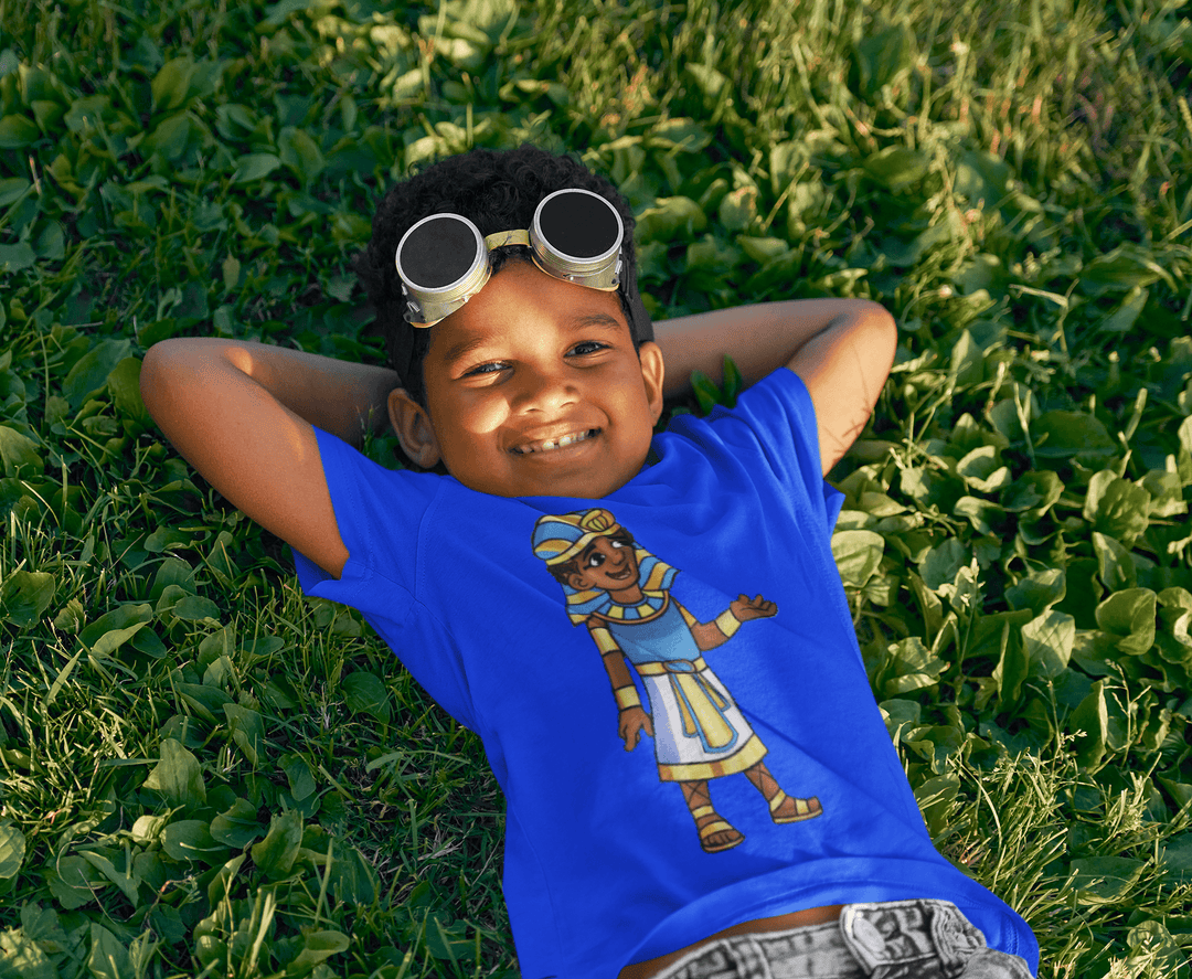 Black boy wearing Tut “Lead With Wisdom” T-shirt from TL Johnson’s Mini Monarchs Apparel; African royalty design for kids and families.