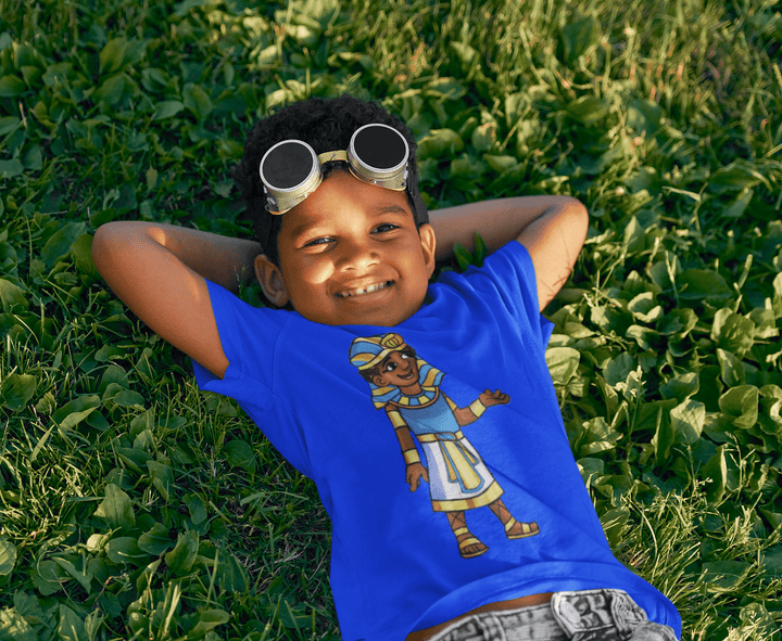 Black boy wearing Tut “Lead With Wisdom” T-shirt from TL Johnson’s Mini Monarchs Apparel; African royalty design for kids and families.
